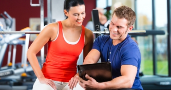 woman and Personal Trainer in fitness gym