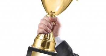 Businessman holding a champion golden trophy on white background